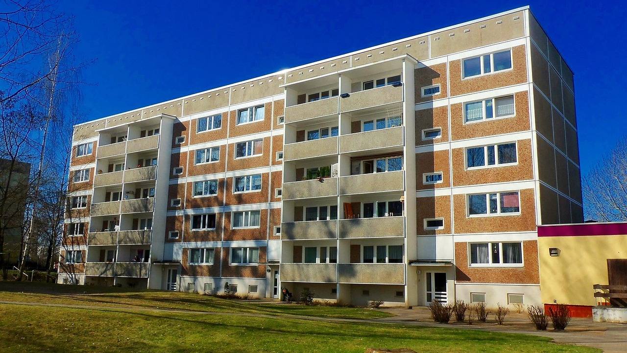 Bloque de pisos de cinco plantas con balcones y césped delante