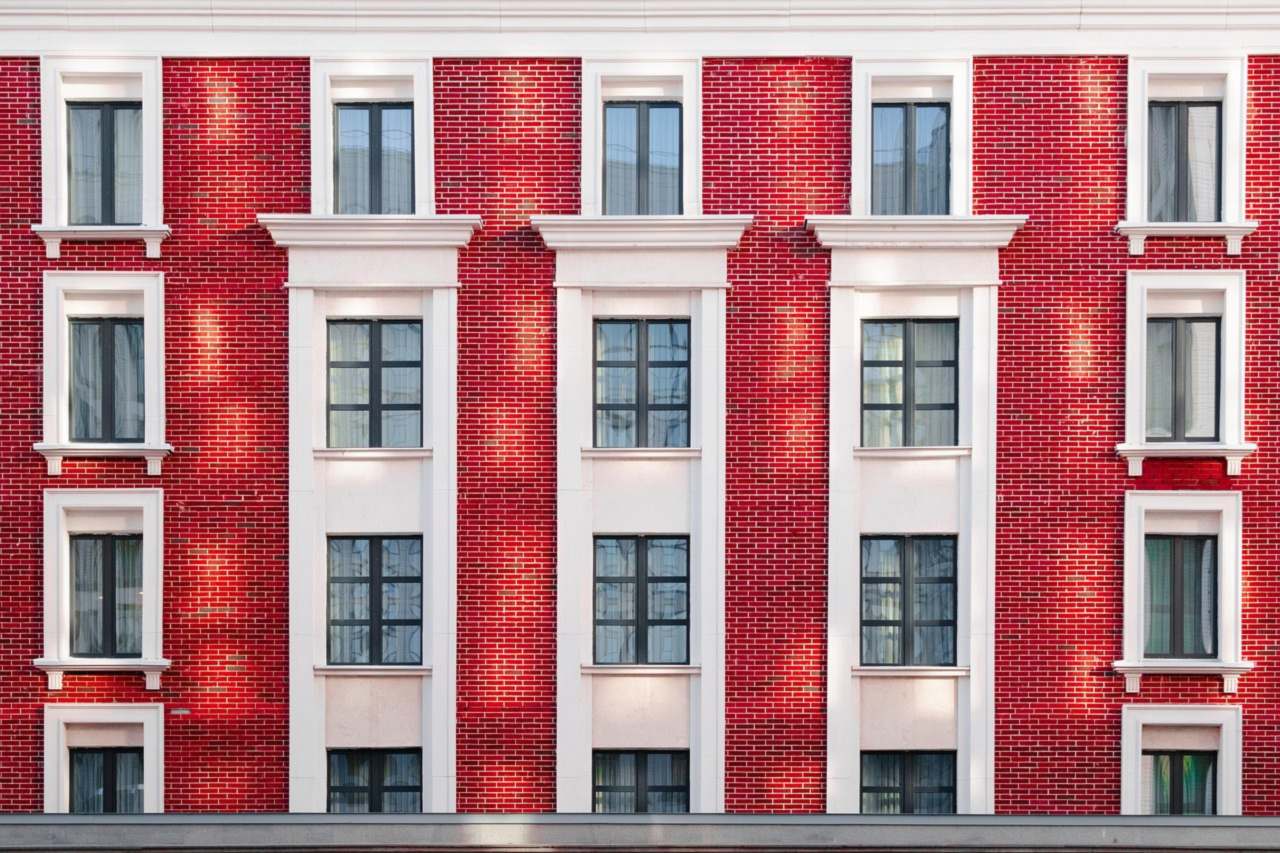 Fachada de un edificio de viviendas de ladrillo rojo con ventanas blancas, imagen ilustrativa de la guía para alquilar un piso en Leganés