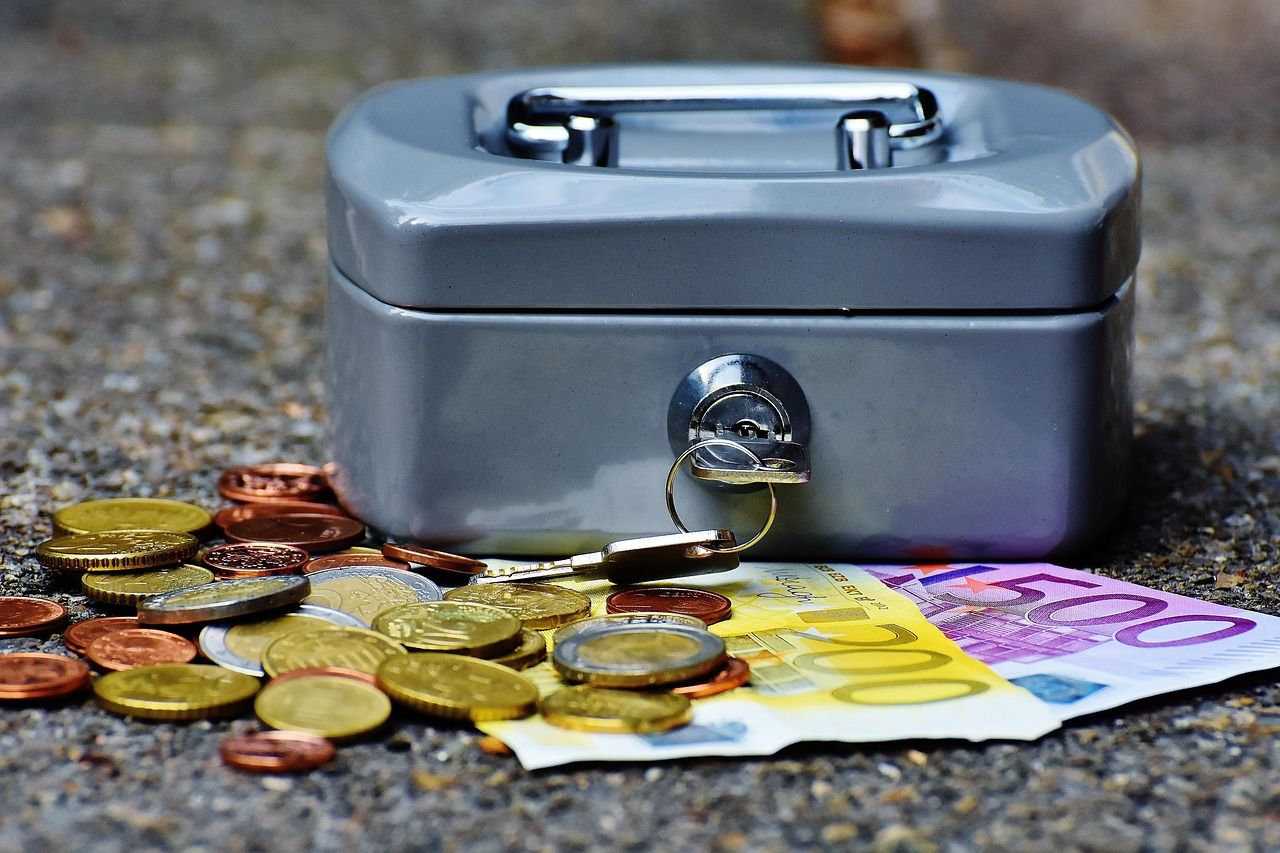 Caja de caudales con llave junto a monedas y billetes de euro, como la fianza del alquiler que se deposita en la Comunidad de Madrid