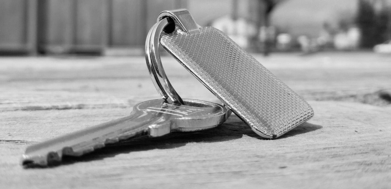 Llave de una vivienda con su llavero sobre una mesa de madera: requisitos del seguro de impago antes de entregar las llaves